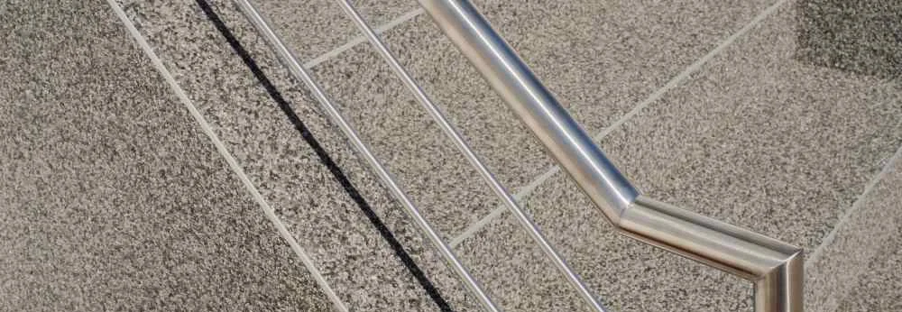 Moderner Handlauf und Edelstahlgeländer an einer Betontreppe mit Kieselbeschichtung